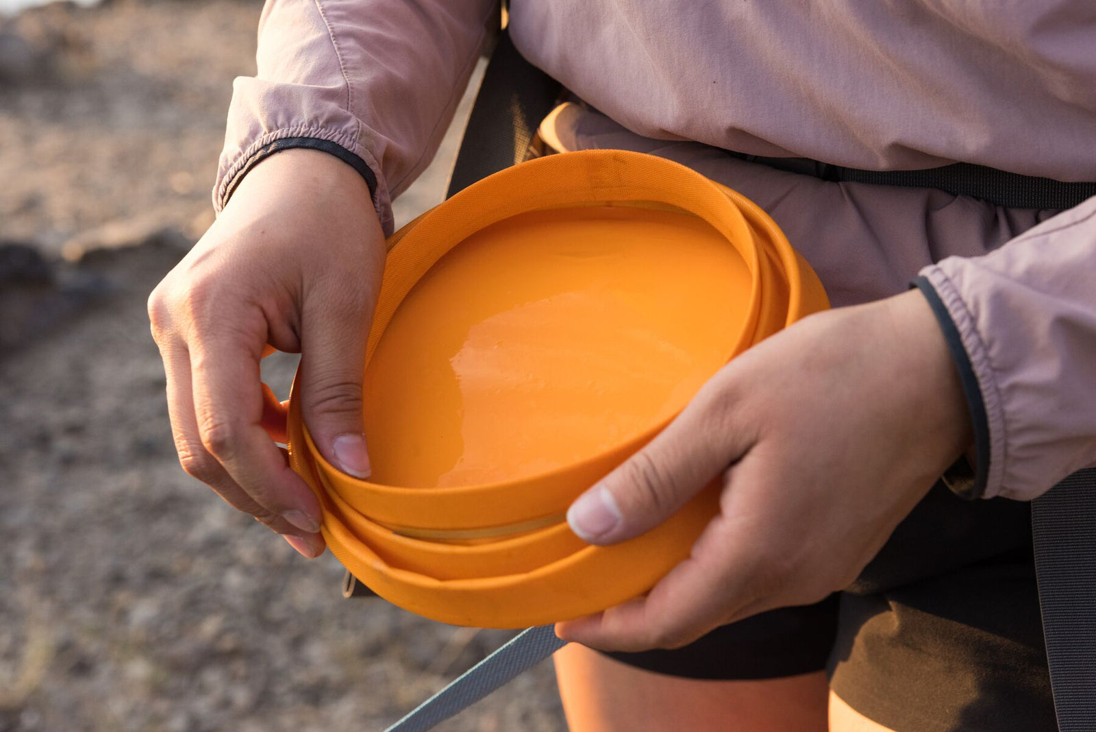 Person collapsing a Ruffwear Bivy Bowl in their hands outdoors