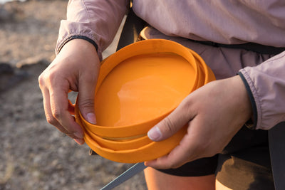 Person collapsing a Ruffwear Bivy Bowl in their hands outdoors