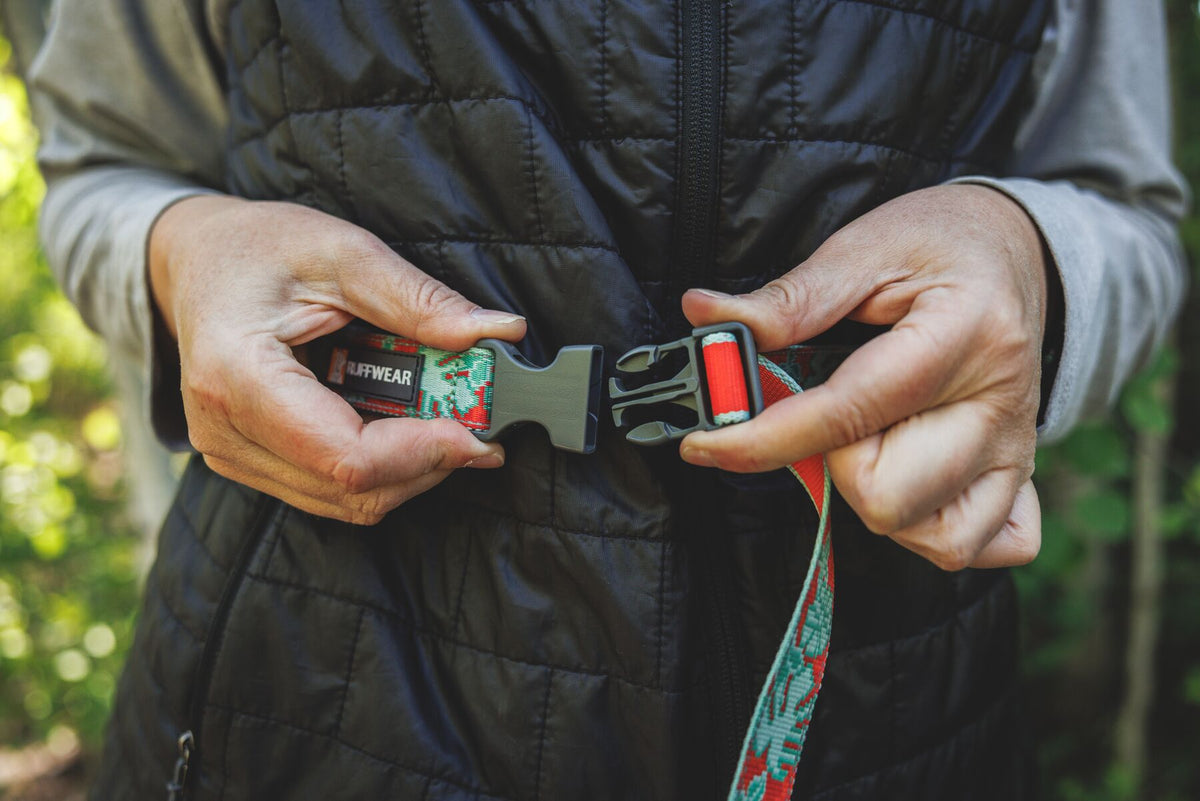 Ruffwear Crag Reflective Lead in Tropical Bloom - person clipping the side-release buckle around their waist to switch to hands-free mode, shown outdoors