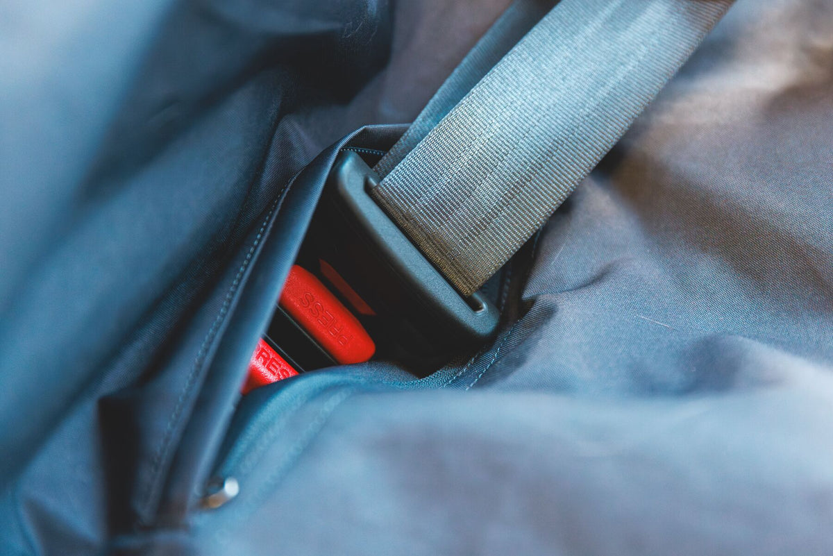 Close-up of a seatbelt buckle threading through the integrated access point of the Ruffwear Dirtbag Seat Cover in Basalt Gray, red buckle release visible, demonstrating that the cover doesn't compromise seatbelt use