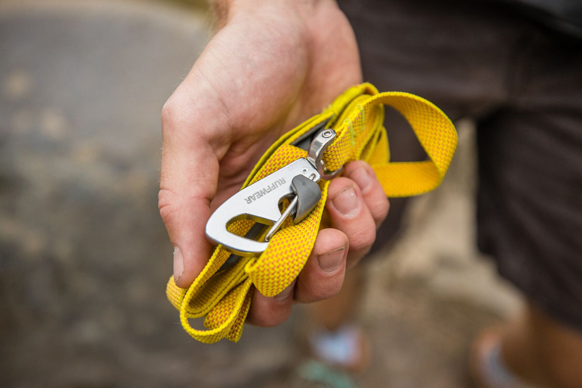 Close-up of a hand holding the Ruffwear Hi &amp; Light Dog Lead in Lichen Green coiled small, showing the lockable Crux Clip