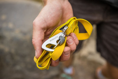 Close-up of a hand holding the Ruffwear Hi & Light Dog Lead in Lichen Green coiled small, showing the lockable Crux Clip