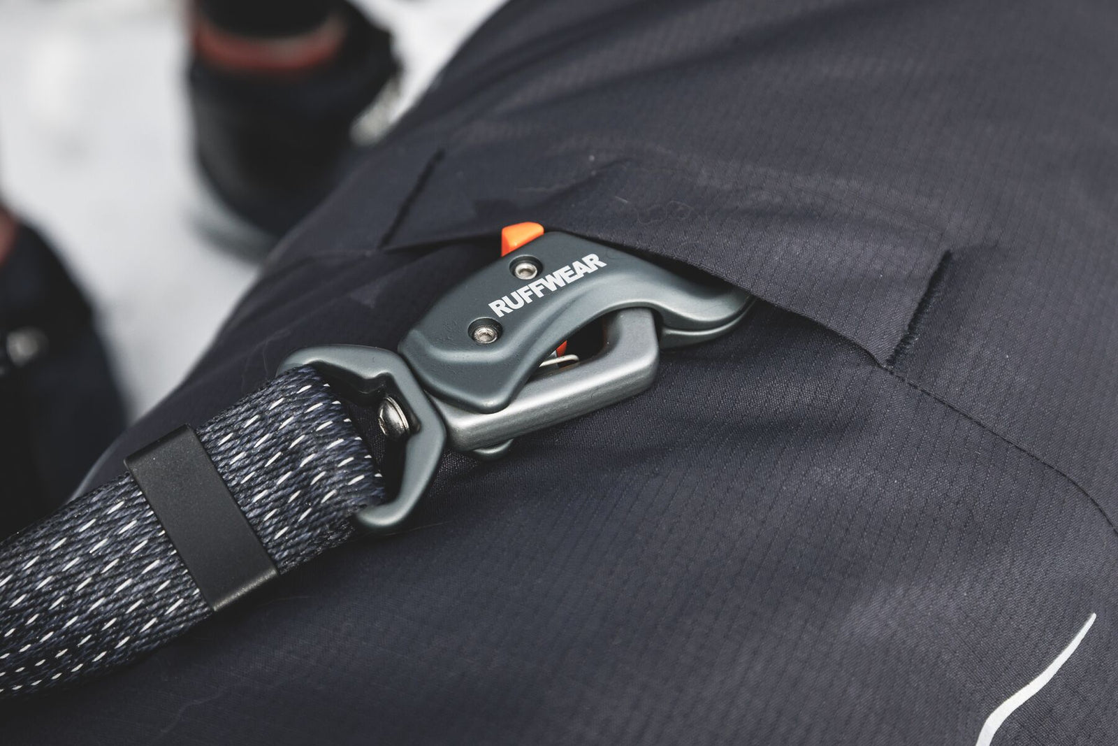 Ruffwear Powder Hound Waterproof Insulated Coverall in Obsidian Black - close-up of the back leash portal with a Ruffwear Ridgeline lead clipped through, showing how the lead attaches over the top of the coverall.