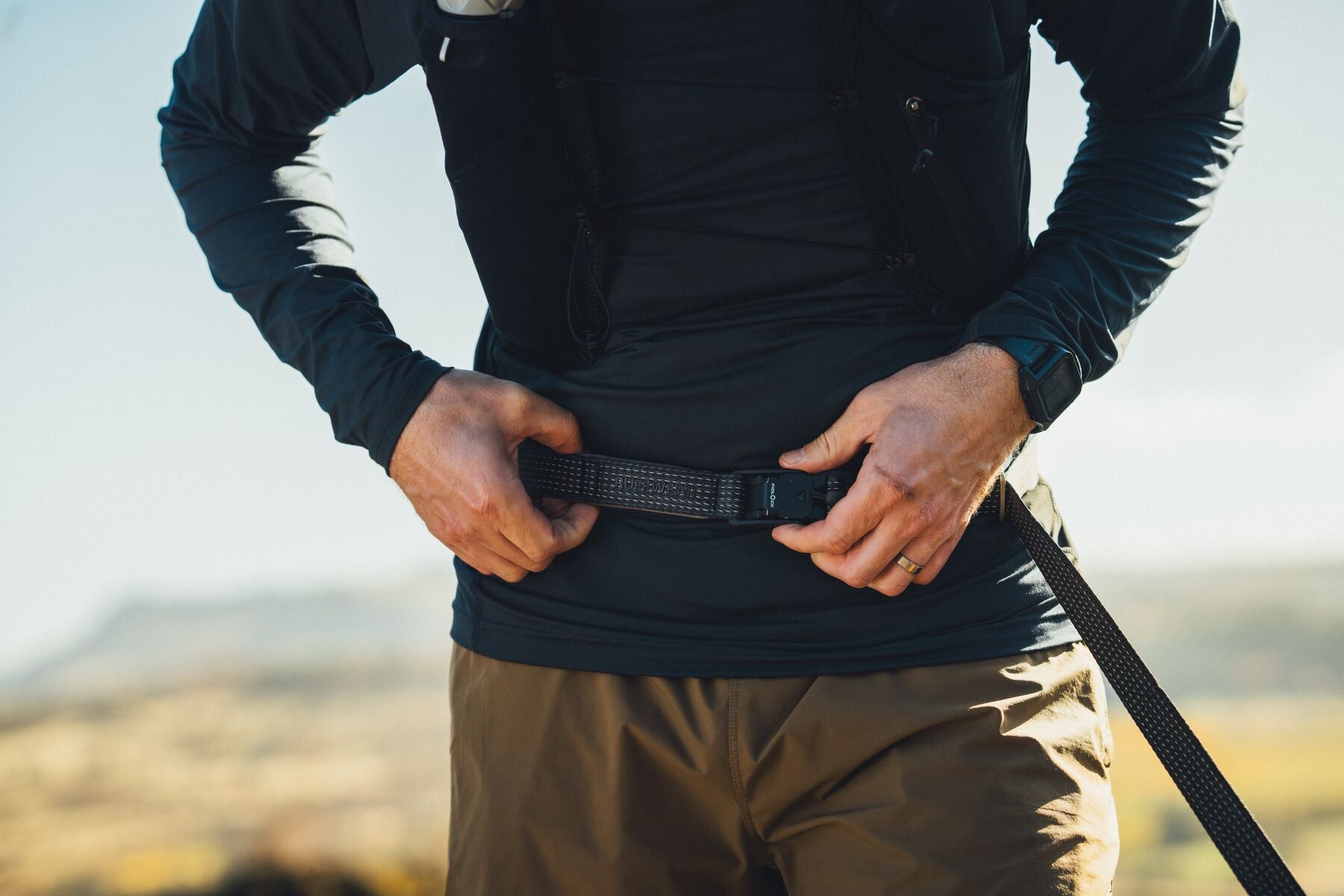 Ruffwear Ridgeline Lead being worn hands-free around the waist on a trail walk with open landscape behind